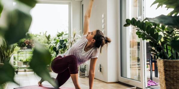 Eine Frau macht zu Hause Yoga auf einer Sportmatte.