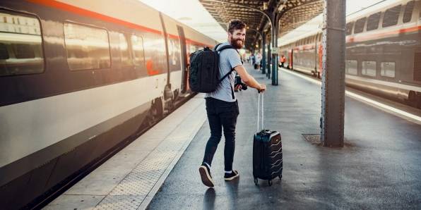 Mann steht an Bahnsteig und ist bereit für seine Reise.