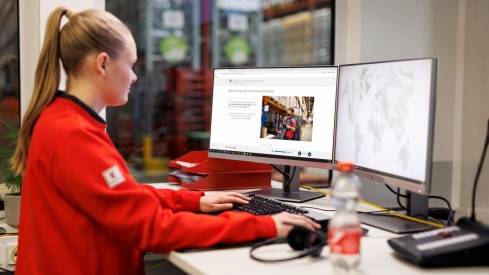 Logistikmitarbeiterin von Kaufland bei der Arbeit am Schreibtisch mit zwei Bildschirmen.